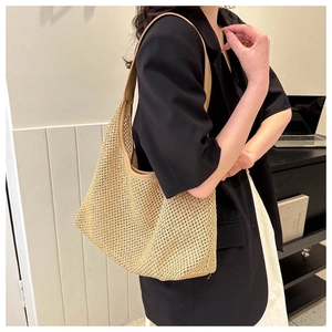 Detail of hand-woven straw shoulder bag with smooth brown leather straps and trim