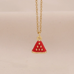 Macro-opname van rode watermeloen hanger met gouden afwerking aan een schakelketting