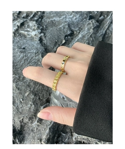 Detail of gold textured rings with colorful stones on a textured rock background
