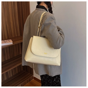 Close-up of beige PU leather shoulder bag with gold chain strap and fashion embossing