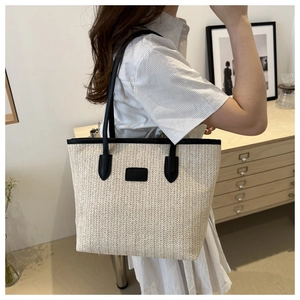 Macro detail of hand-woven straw tote with premium black leather straps and V-shaped texture