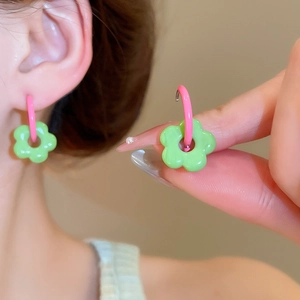 Detailed close-up of pink ear hooks and green glass flower charms on elegant earrings