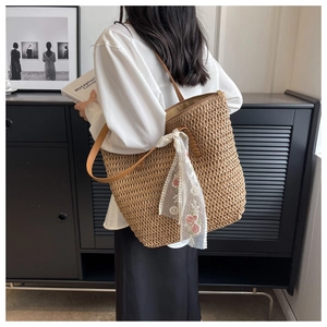 Dettaglio borsa tote in paglia intrecciata con tracolla in pelle marrone e sciarpa di pizzo