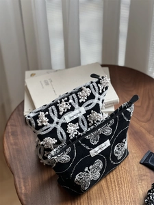 Detail of black cotton canvas makeup bags with butterfly embroidery and zipper closure