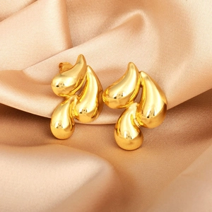 Macro shot of 18K gold irregular teardrop earrings on champagne satin fabric
