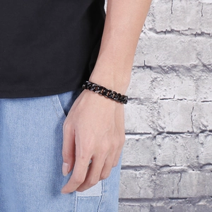 Gros plan d'un bracelet gourmette en acier inoxydable noir mat porté par un homme