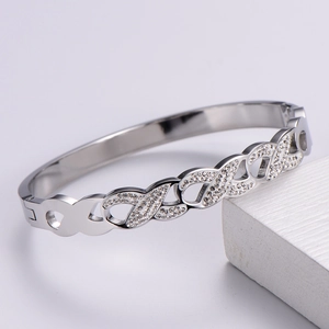 Macro shot of silver titanium steel bangle with infinity cross design and inlaid rhinestones