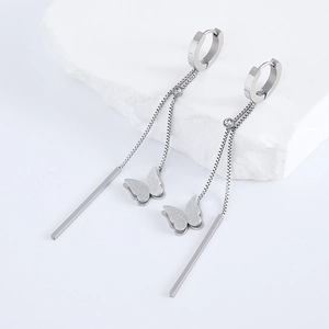 Detail view of silver tassel earrings with matte butterfly and long bar on white stone