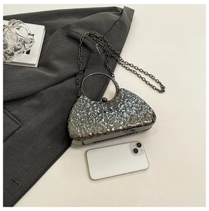 Clutch da sera argento con trama a onde mostrata accanto a un telefono per le dimensioni