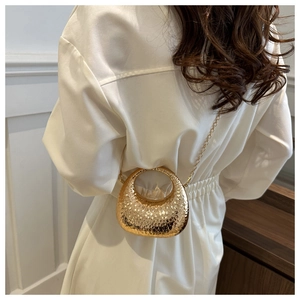 Détail du sac bandoulière doré en croissant avec texture martelée et chaîne en métal