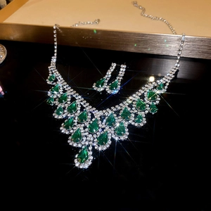 Detailed macro of green waterdrop pendant necklace and matching diamond earrings