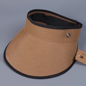 Detail view of woven linen straw sun visor with black trim and silver metal logo emblem