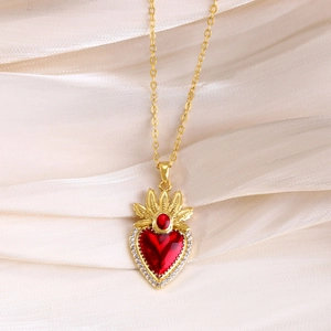 Detail of red heart ruby pendant with gold crown setting on white satin fabric