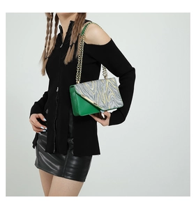 Detail of green leather flap and marble texture body on the shoulder bag with chain strap