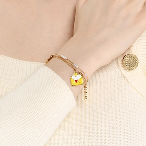 Detail of gold double-layer bracelet with pearls and Merry Christmas envelope charm