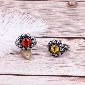 Detail of punk style skull rings with red and yellow evil eyes on vintage wood