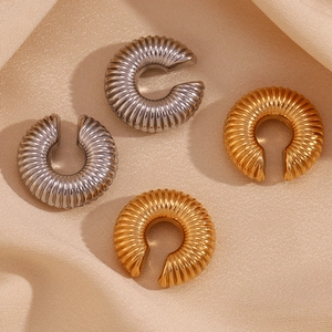 Detailed view of textured hollow twisted C-shape earrings in gold and silver finish