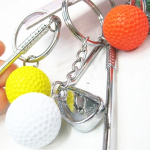Close-up van kleurrijke golfbal sleutelhangers met metalen clubs en textuurballen.