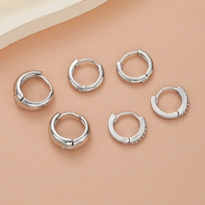 Detailed view of three pairs of silver-toned hoop earrings with zircon inlay details