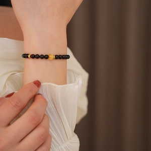 Detail of sandalwood bracelet with amber bead on wrist against warm background