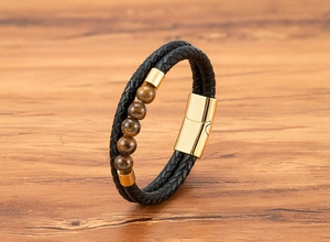 Close-up of black braided leather bracelet with tiger eye beads and gold magnetic clasp