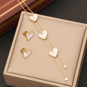 Golden stainless steel heart jewelry set with white shell inlay on a jewelry box cushion
