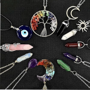 Assortment of hexagonal crystal pendants with tree of life and moon motifs on black background