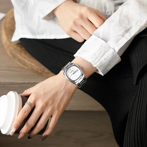 Detail of a square stainless steel quartz watch with dual calendar display and silver strap