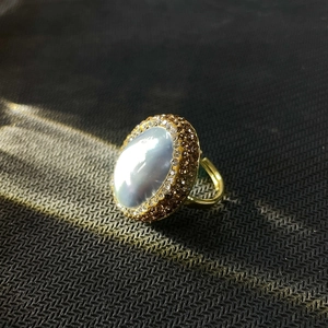 Macro detail of vintage gold ring with oval mother-of-pearl stone and pavé crystal border