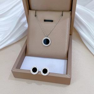 Detail of round black agate necklace and earrings set in a premium beige jewelry box