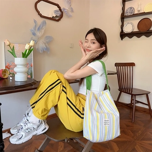 Détail du grand sac cabas en toile rayé avec poignées vertes et étiquette de marque