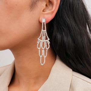 Macro detail of luxury fan-shaped tassel earrings with pavé crystals on a female model
