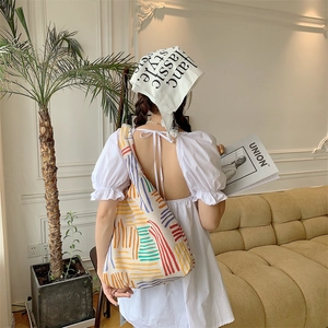 Detailed knit texture and color-block striped pattern on the large canvas shoulder bag