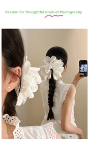 Detailed view of a large white lace flower hair clip with pearl center on braided hair