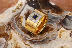 Macro shot of gold-plated wide ring featuring a square blue sapphire and diamond halo