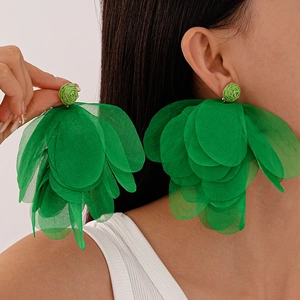 Detailed macro view of large green layered fabric flower earrings worn by a female model