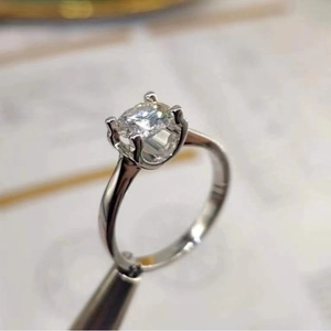Macro shot of a classic six-prong silver ring with a one-carat round brilliant cut stone.