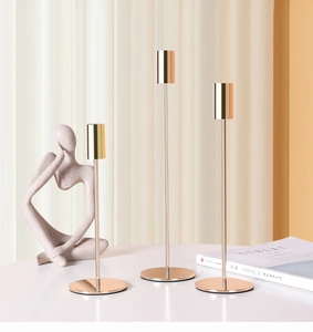 Detailed view of three polished gold metal candlesticks in varying heights for home decor