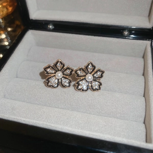 Macro detail of floral stud earring with black enamel petals and a central white pearl