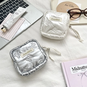 Detail of square quilted sanitary pouches in pearl white and silver with butterfly texture
