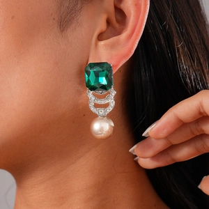 Detail of green emerald-cut crystal earrings with elegant white pearl drops