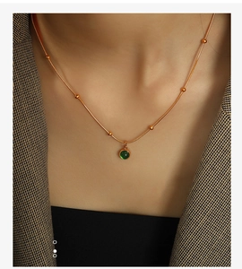 Close-up of a vintage green aventurine round pendant necklace worn on a gold titanium chain