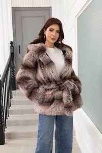Close-up of textured faux fur coat with hooded design and belted waist in a brown finish