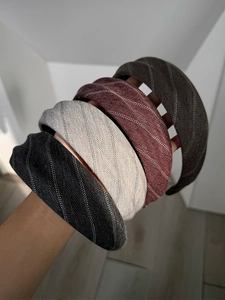 Detailed view of four striped fabric headbands in black, grey, burgundy and brown colors