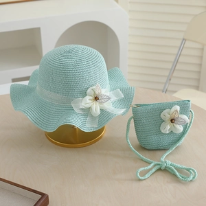 Close-up of mint green woven straw hat and matching bag with delicate lace flower details