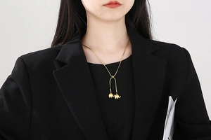 Detail of adjustable gold snake chain featuring twin elephant pendants on a black blazer