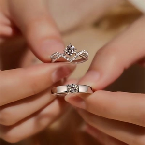 Close-up of couple crown rings with four-prong set 1 carat zircon stones on hand