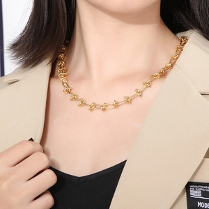 Collier double chaîne dorée avec détail de nœud et boucle en U porté par un mannequin