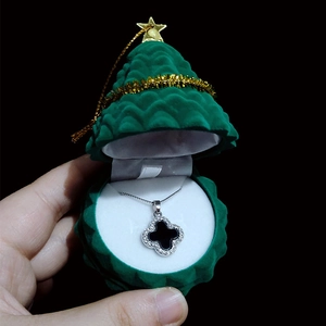 Detailed close-up of a green Christmas tree jewelry box with a four-leaf clover necklace