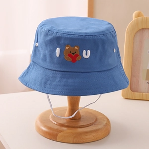 Close-up of blue cotton bucket hat featuring bear embroidery and white elastic chin strap